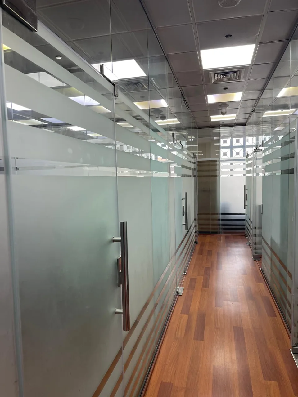 Office corridor with glass partitions and a wood-effect floor